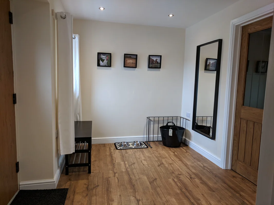 Clean dog-friendly room with feeding bowls, basket, and framed wall art.